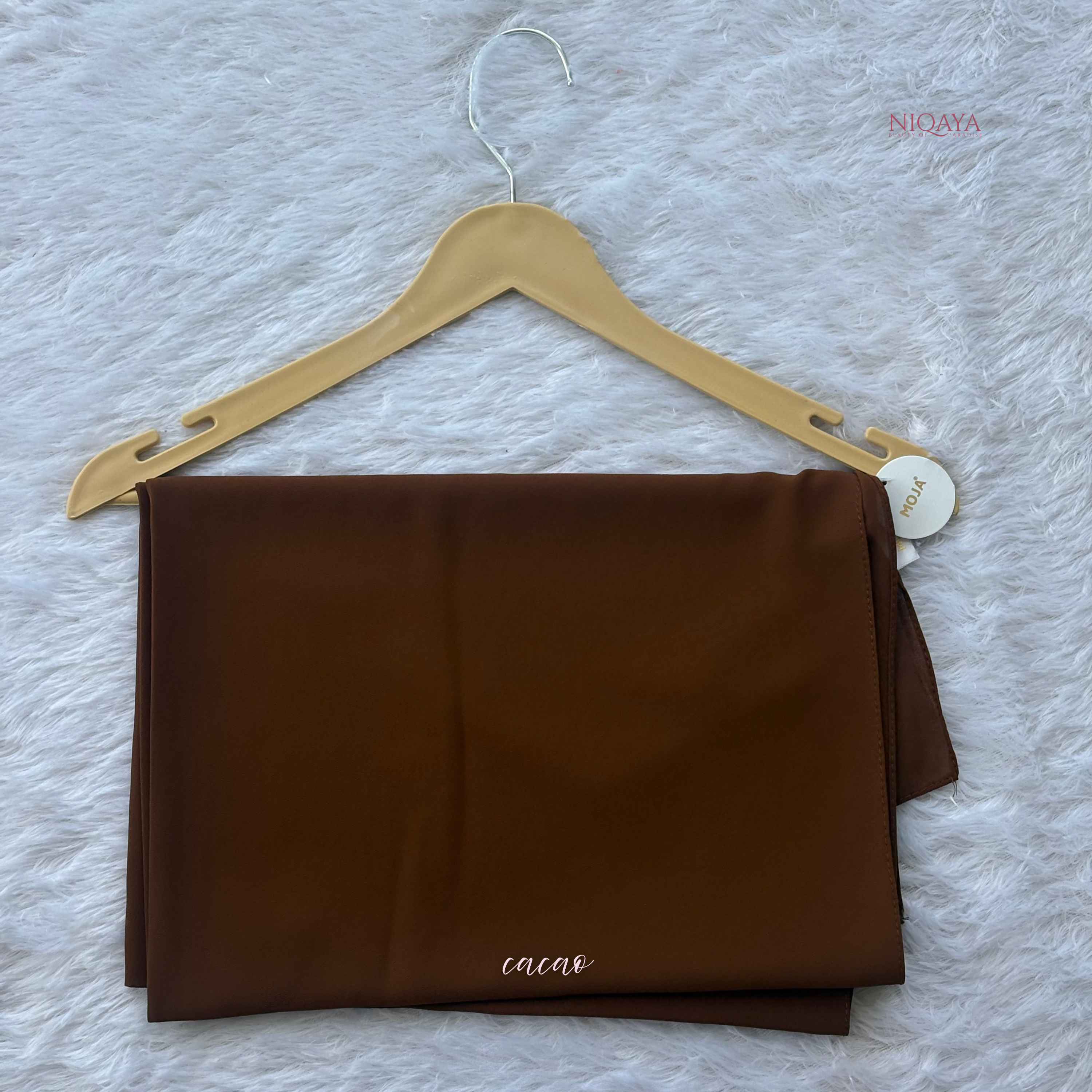 Brown fabric on a hanger with 'cacao' label on a textured white background