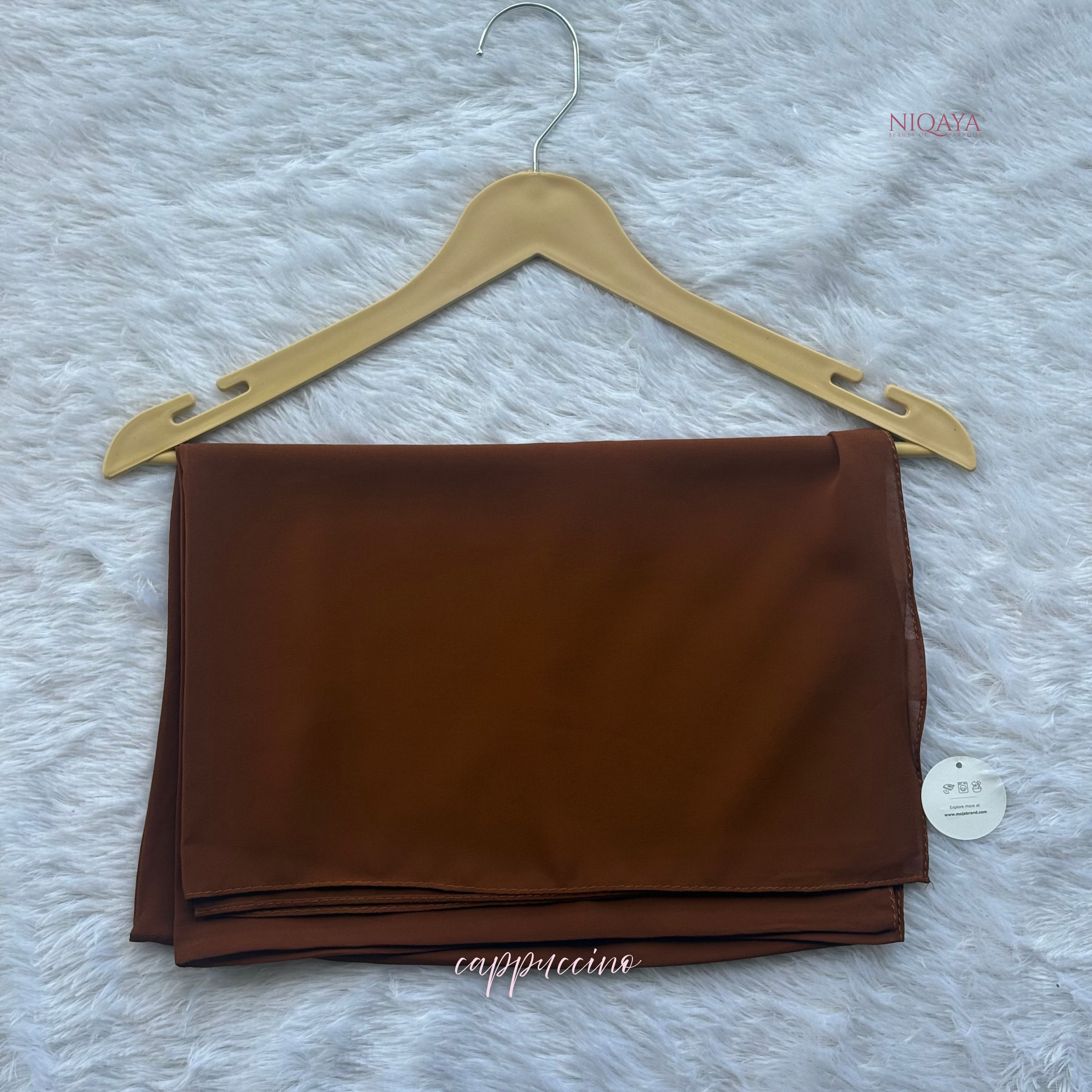 Brown fabric on a hanger with 'NIQATA' branding on a textured gray background