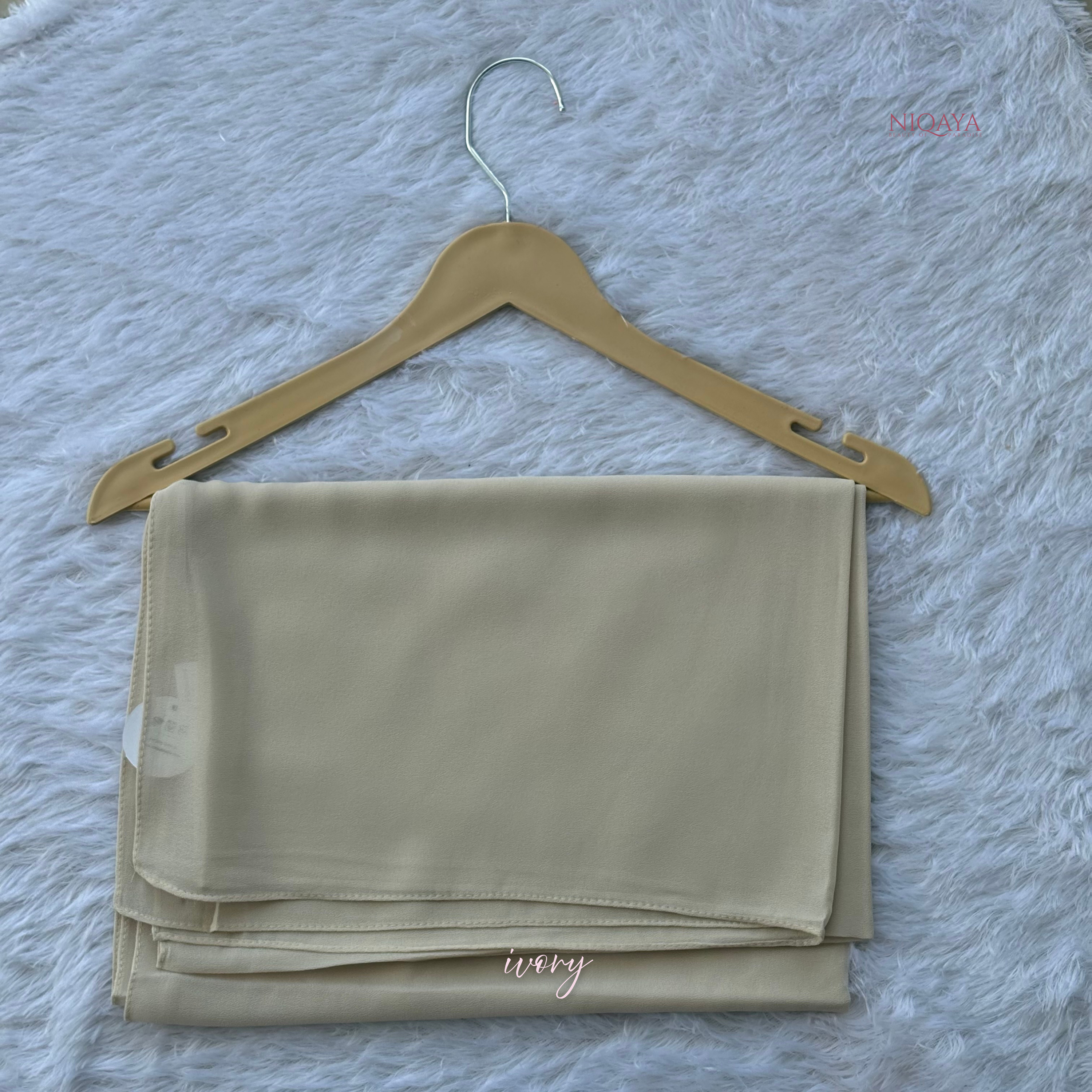 Folded beige fabric on a hanger against a textured gray background