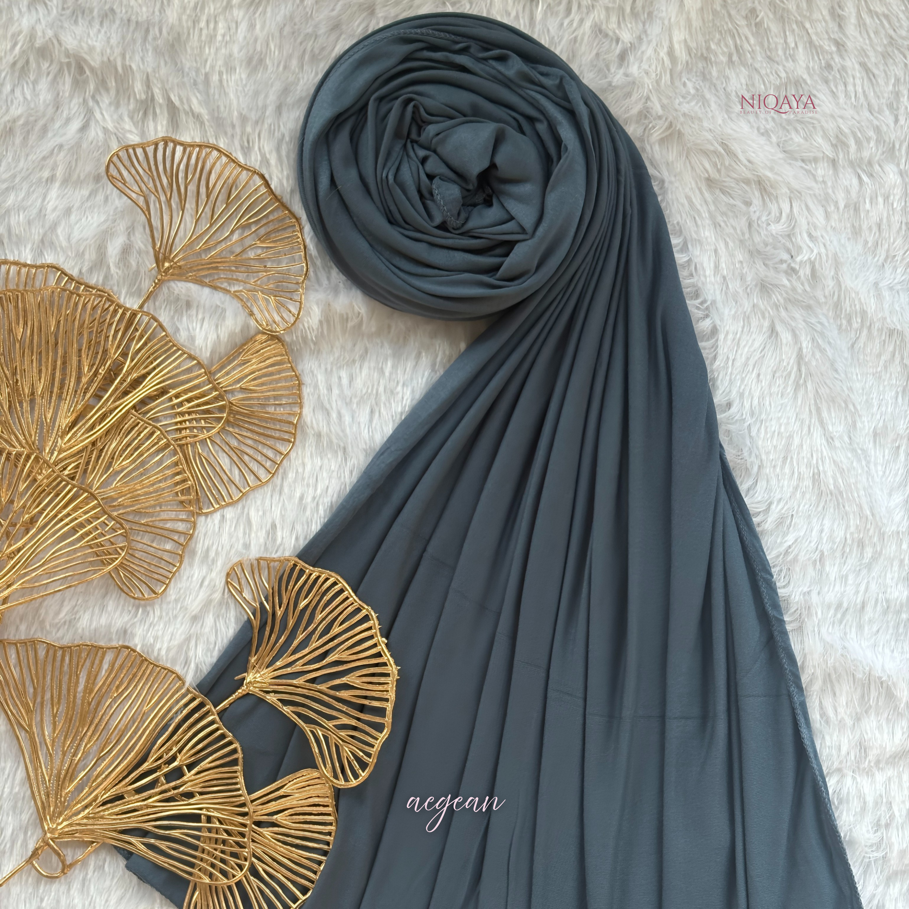Dark gray hijab with gold leaf decorations on a textured surface