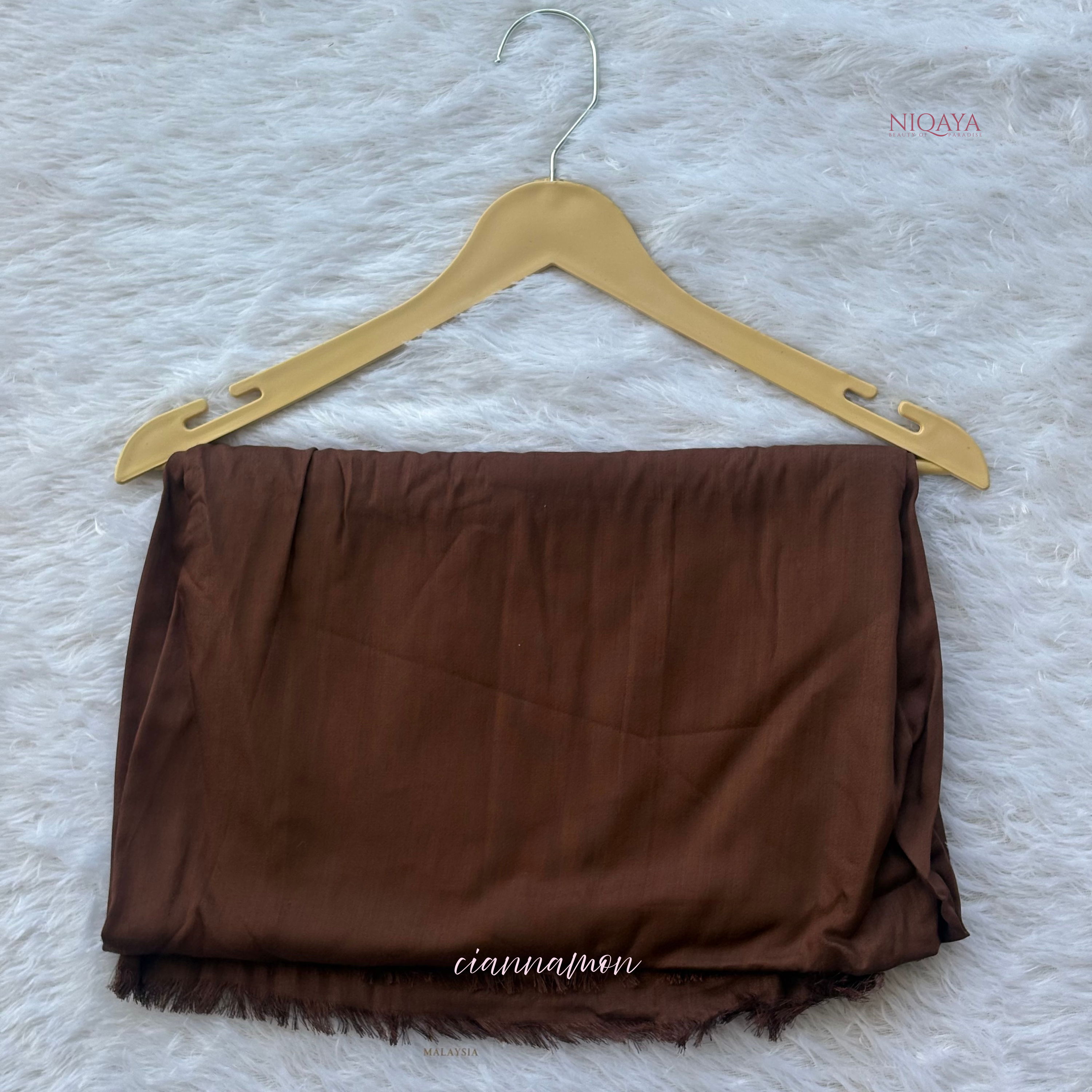 Brown fabric on a hanger against a textured white background