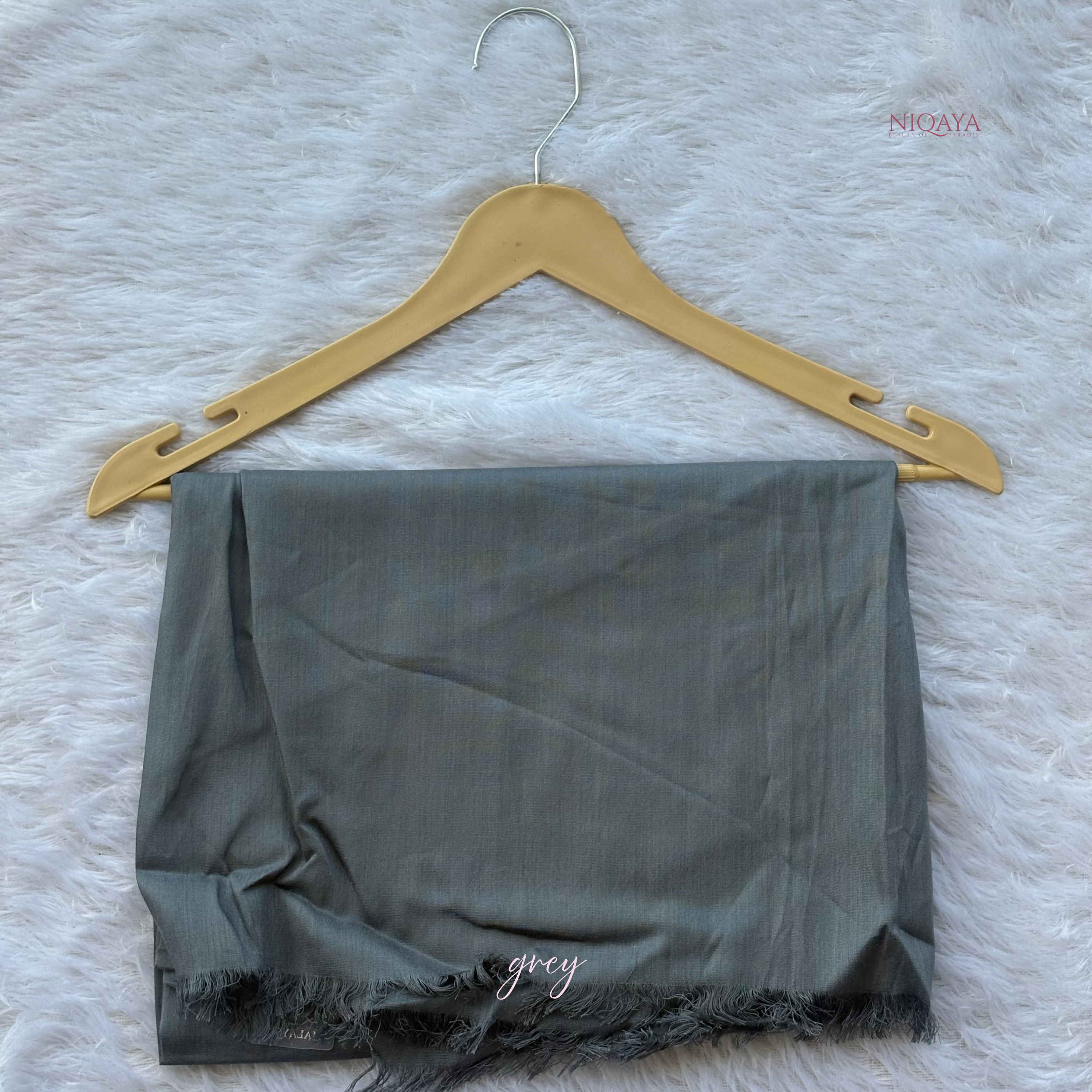 Gray fabric on a wooden hanger against a textured white background