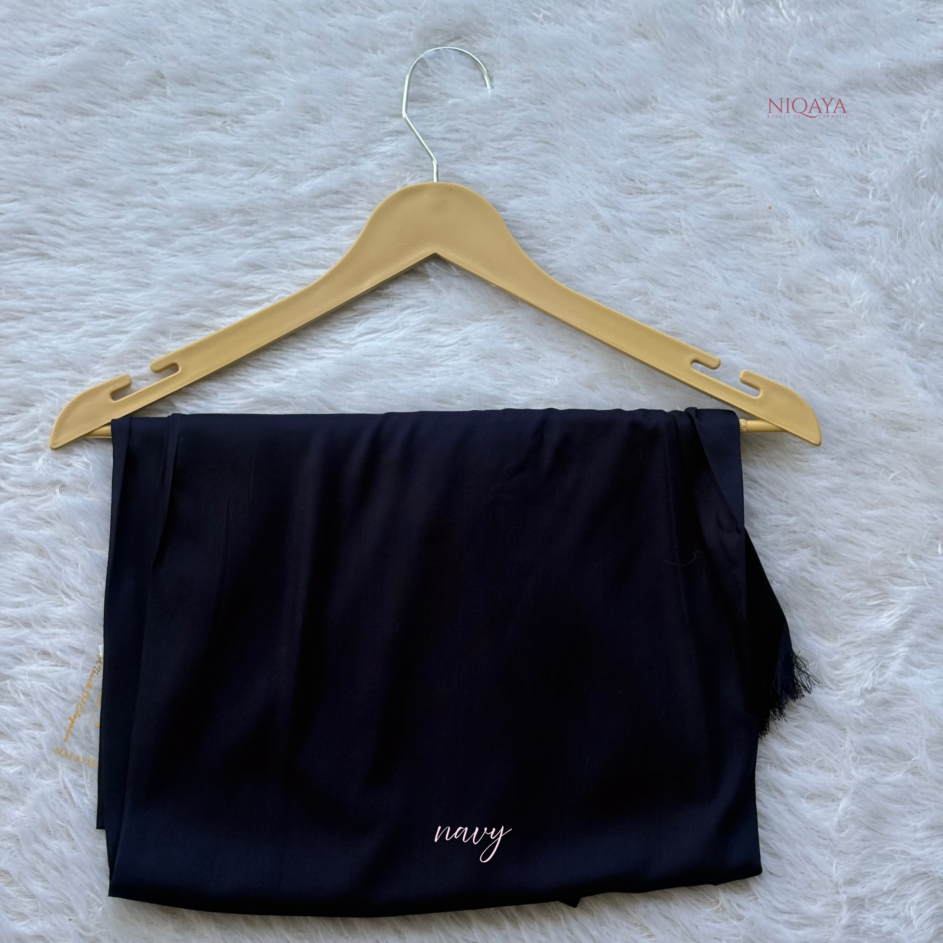Navy top on a wooden hanger against a textured white background