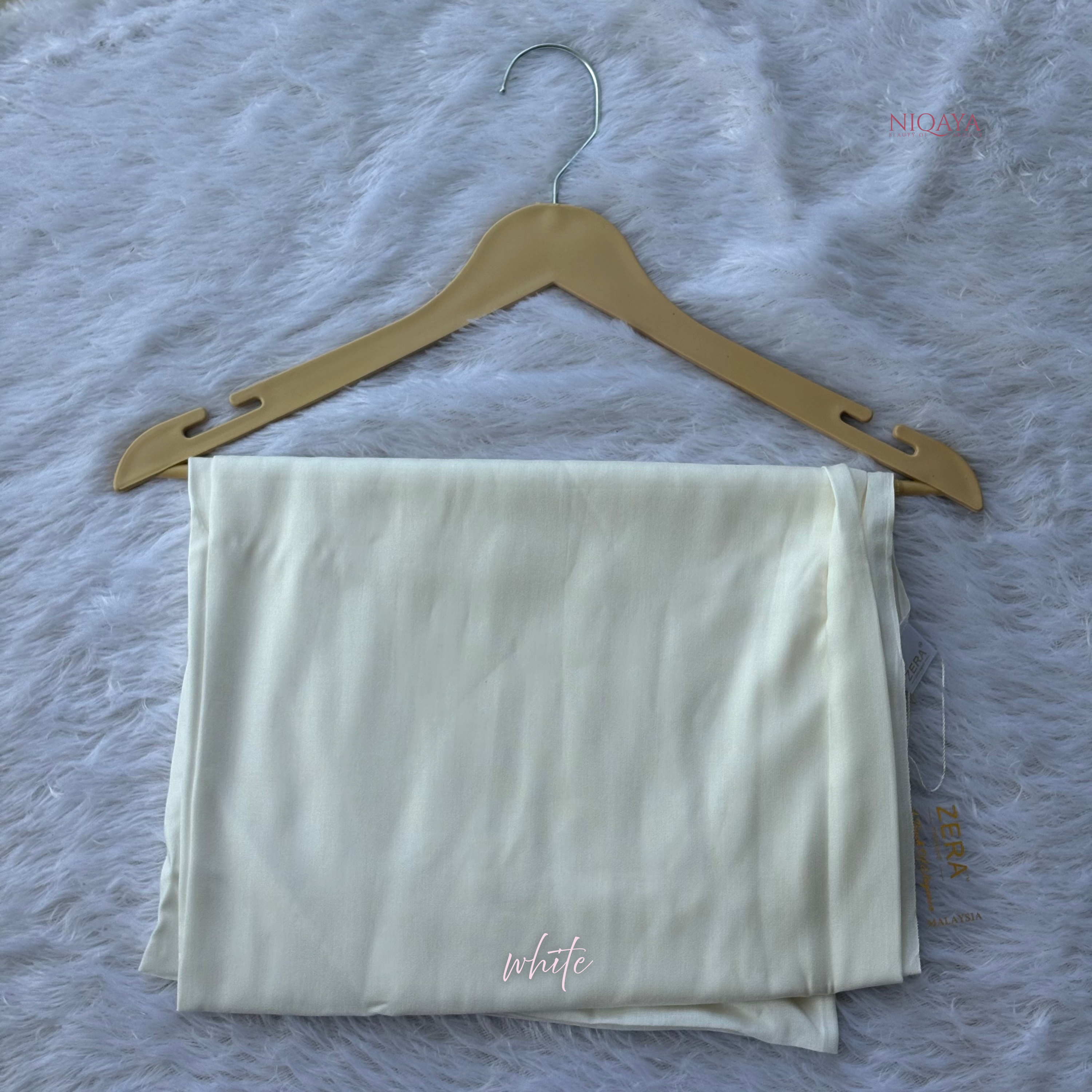 Folded white shirt on a beige hanger against a textured gray background